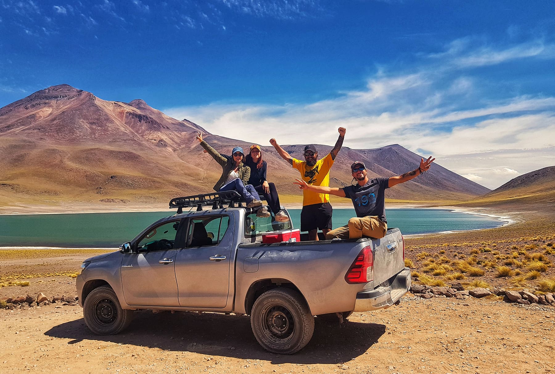 A equipe da On The Road junto à lagoa Cejar, com flamingos alçando voo sobre o salar.